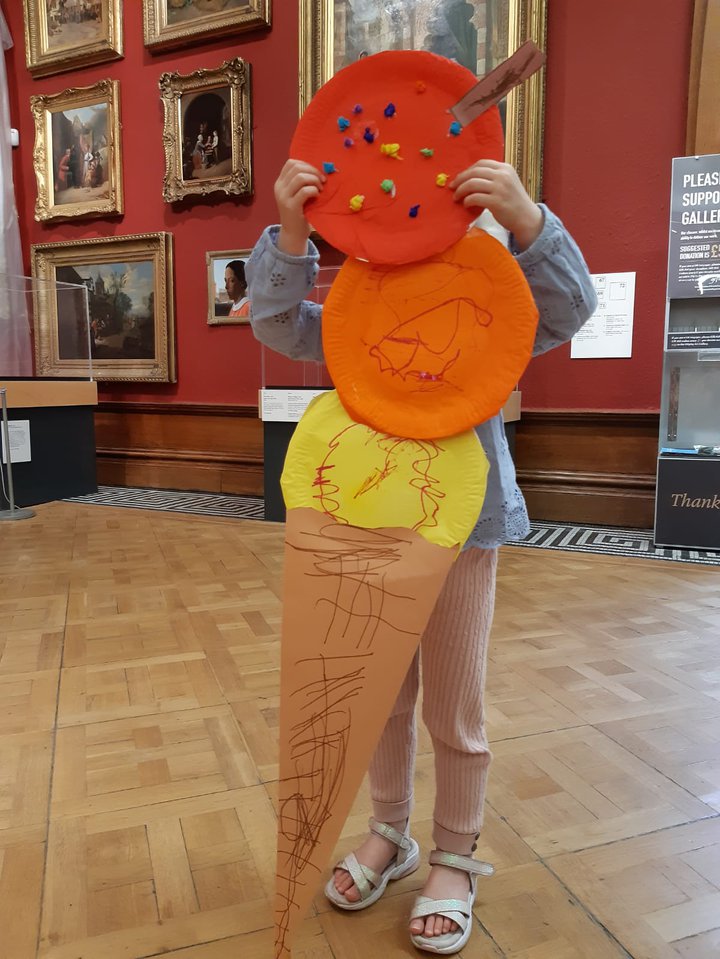 A photograph of a child holding a large paper ice cream