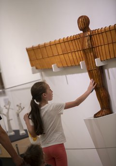 A young girl touching the Angel of the North maquette