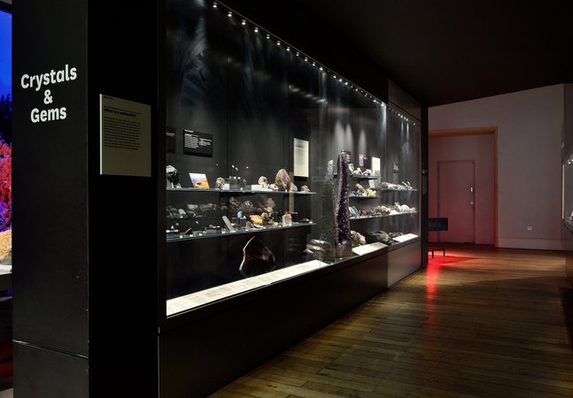  A glass museum case full of different crystals and gemstones