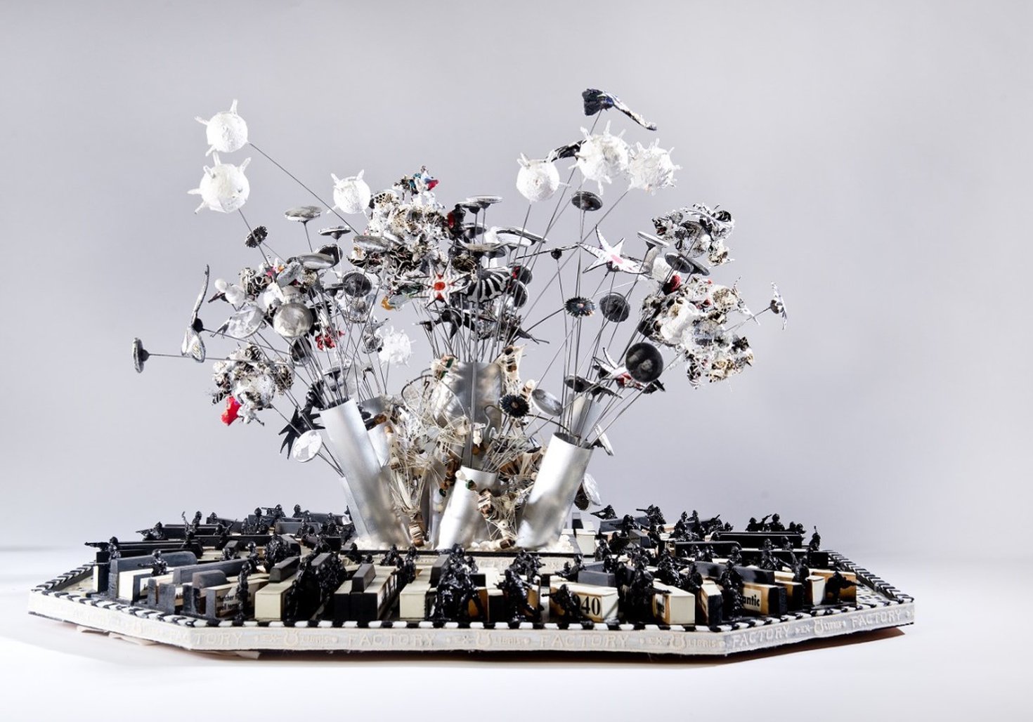 silver sculpture piece with silver wires and piano keys 