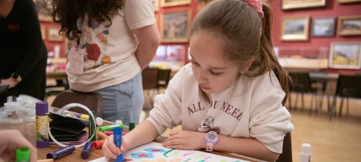 A child sitting and drawing in a large gallery space
