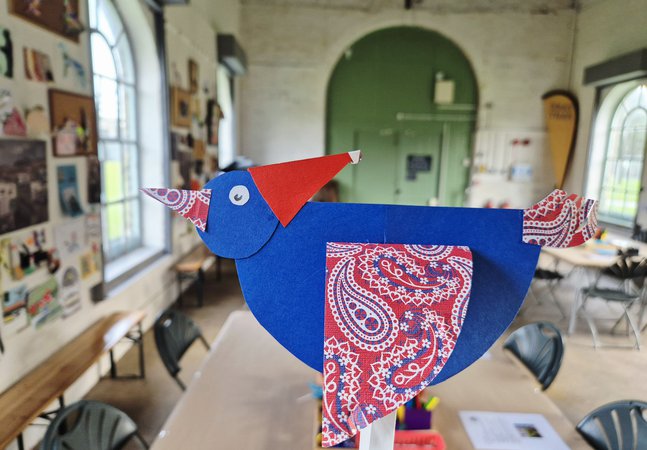 A piegoen made out of paper wearing a santa hat