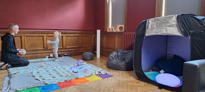An adult and child throwing a ball to each other in a play space.