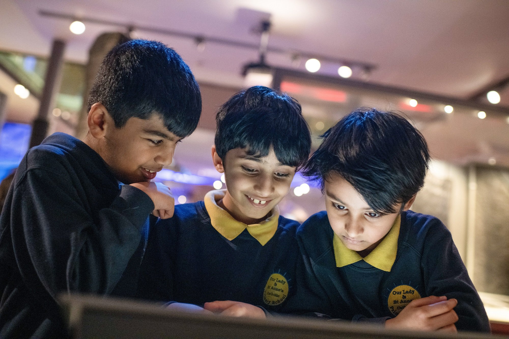 Three schoolboys looking at an interactive display in a museum.