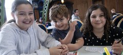 two girls and a boy smile while doing crafts 