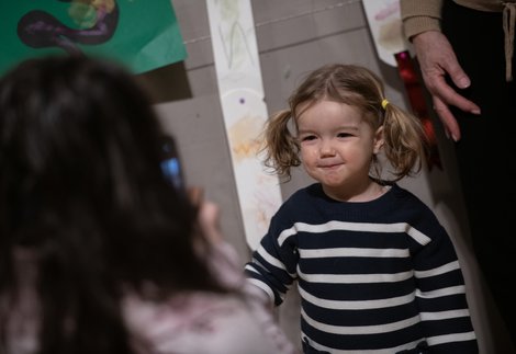 A child wearing a navy and white striped jumper, smiling at a person behind the camera
