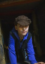 A child crawls through a museum display of a coal mine wearing a flat cap