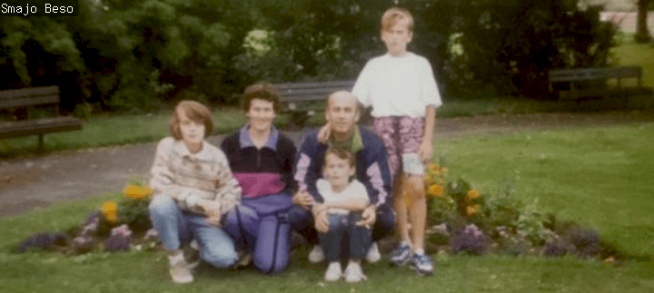 A grainy 1990s photo of a family smiling 