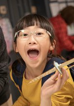 girl in Play Invent gallery holds her creation and laughs at camera 