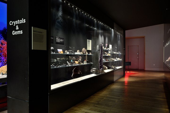 A glass museum case full of different crystals and gemstones
