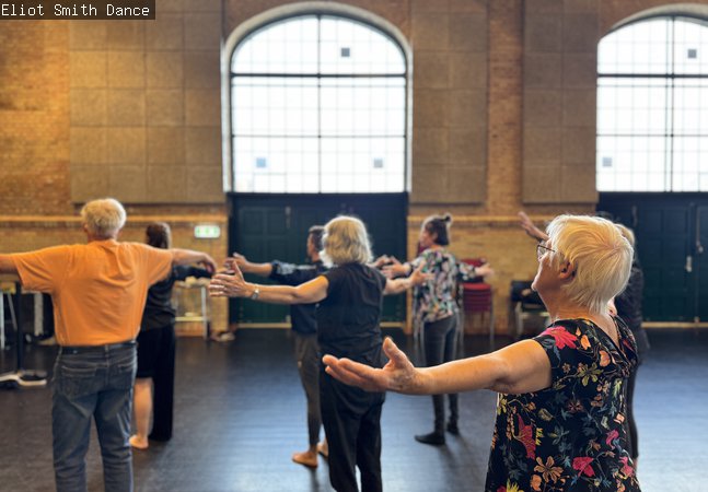 People standing inside a room with their arms wide out in dance 