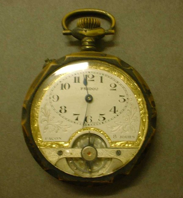 This is a pocket watch has a cream face with gilt decoration and black numbers.