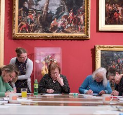 group of people making art in front of beautiful paintings