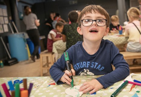 A young boy doing a craft activity in a museum