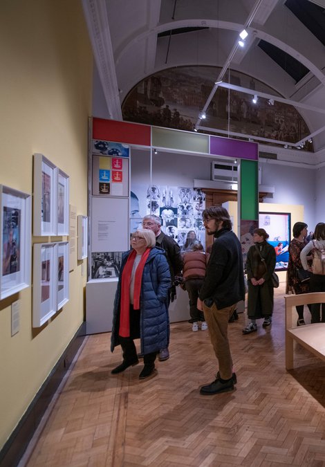 A younger man and older woman looking at a photograph on the wall.