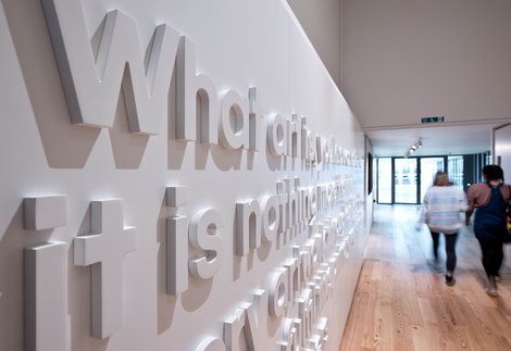 Two people walk past a wall at Hatton Gallery