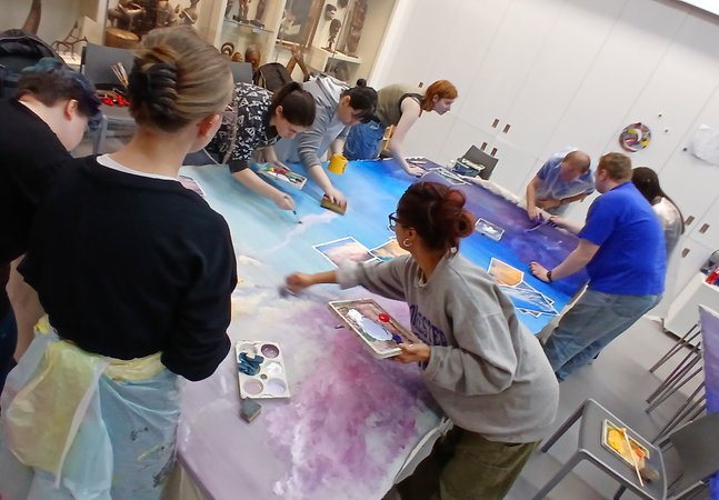 L-INK group are creating artwork together on a large table.