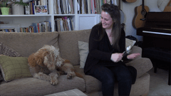 A photo of a woman sitting on a sofa looking at her dog