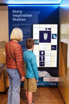 An adult and a child are looking at the interactive Story Inspiration Station in the Great North Museum Hancocks Living Planet Gallery