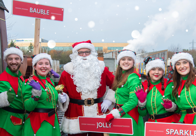 Elves and Santa smiling at the platform at Stephenson Steam Railway