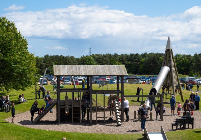 An outdoor playground with parents and children playing