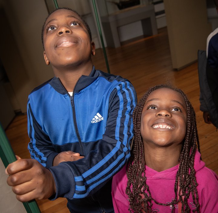 boy and gilr smile up towards camera in gallery