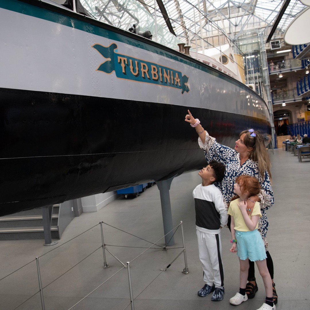 Three people looking at a ship in a museum Three people looking at a ship in a museum