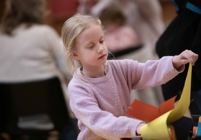 A girl with long blonde hair taking part in a craft activity