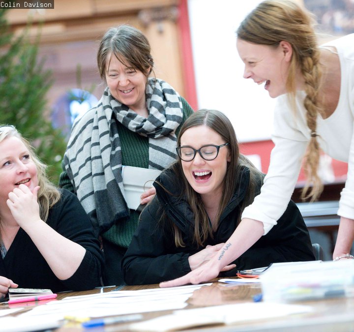 Four people around a table laughing. 