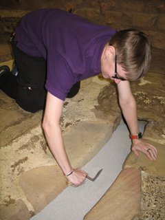 Person using a trowel to excavate a replica drain