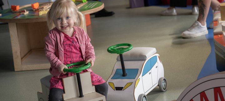 little smiling toddler on toy car