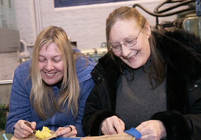 two women smile and talk in the museum