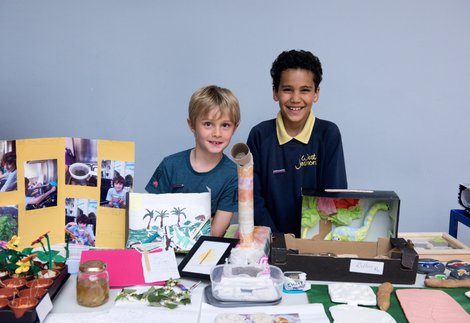 Two schoolchildren standing at a stall with their science project