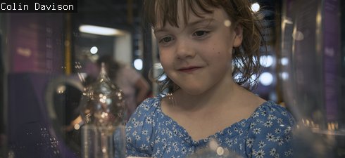 girl stands in front of lightbulbs case 