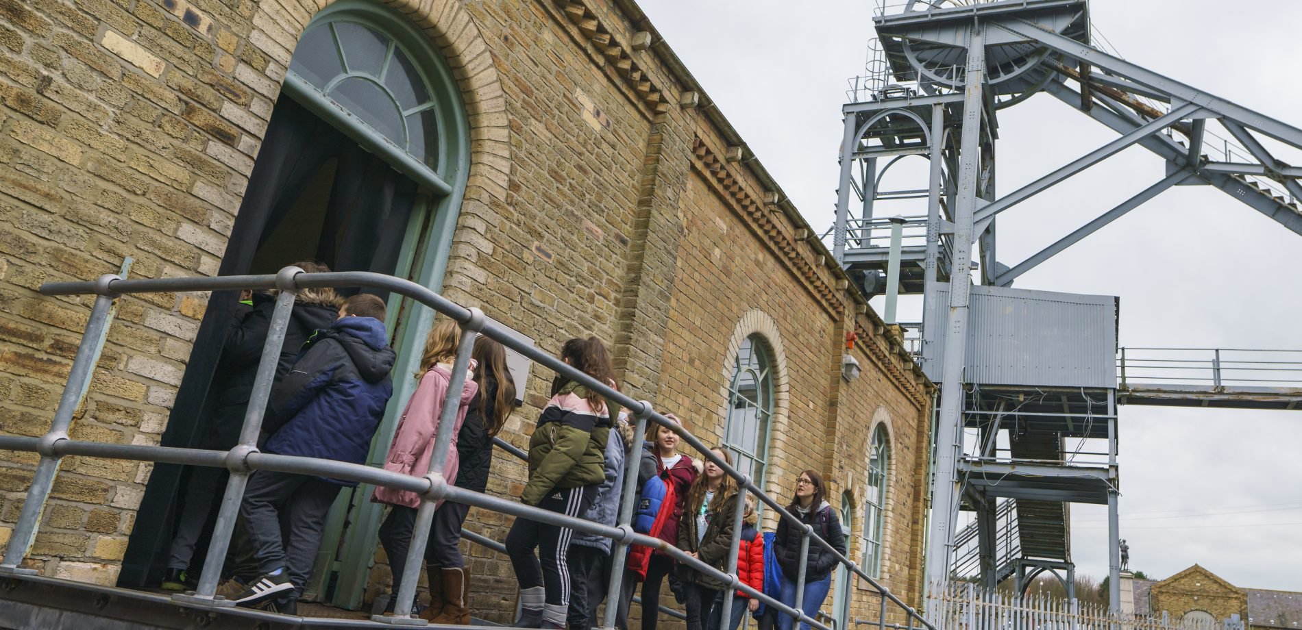 A group of school children walking up a ramp to enter a colliery building at Woodhorn Museum