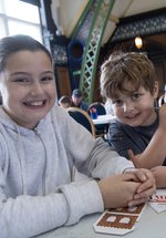 two girls and a boy smile while doing crafts 