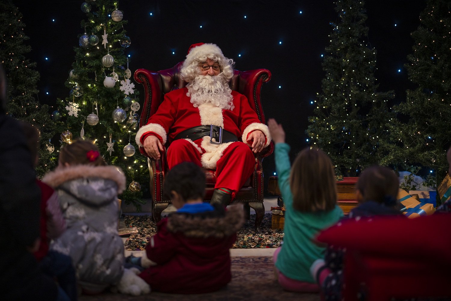 Santa on a large seat, children sit at his feet. Santa on a large seat, children sit at his feet.