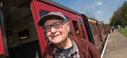 Man wearing cap standing next to railway carriage