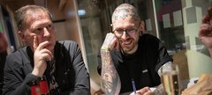 two men sit a table playing a quiz, laughing