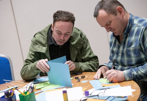 Two people sitting at a table and taking part in a activity together.