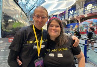 2 volunteers in Discovery Museum atrium smiling at camera