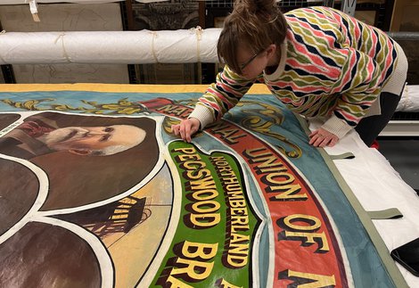 A person conserving a hand painted mining banner.