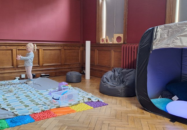 An adult and child throwing a ball to each other in a play space.